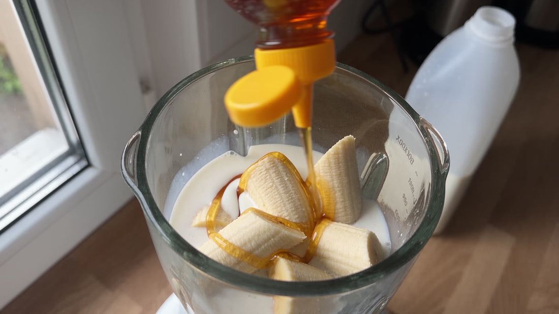 Honig läuft über Bananenstücke in einen Glasmixer mit Milch und Sahne – Zutaten für den Masseshake mit 2.060 kcal